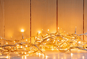 Weihnachtsbeleuchtung: gelb strahlende Lichterkette auf einem weißen Fußboden vor einer weiß getäftelten Wand