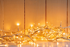Zur Weihnachtsbeleuchtung dürfen Lichterketten nicht fehlen Weihnachtsbeleuchtung: gelb strahlende Lichterkette auf einem weißen Fußboden vor einer weiß getäftelten Wand