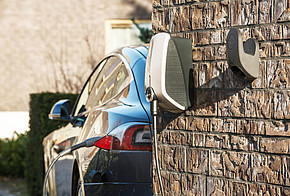 Photovoltaik-Eigenverbrauch: Tankstelle für Elektroauto Tankstelle für ein Elektroauto an einer Hauswand, Elektroauto mit Ladekabel im Hintergrund