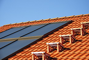 Dach mit Solarzellen Fördermittel der KfW: Dach mit roten Dachziegeln und Solarzellen