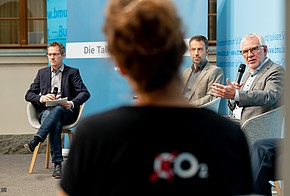 Podium beim Klimatalk von co2online: Tanja Loitz von hinten im Vordergrund und drei Diskutanten im Hintergrund