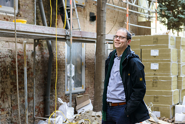 Heizspiegel-Botschafter Till Eichmann vor einem Gebäude, dessen Fassade gedämmt und saniert wird.